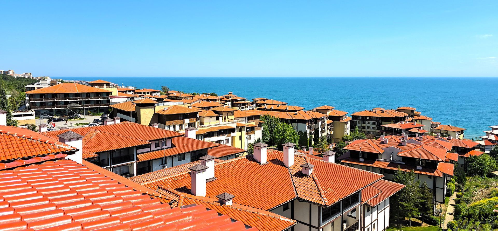 A city with red tiled roofs and a view of the ocean.