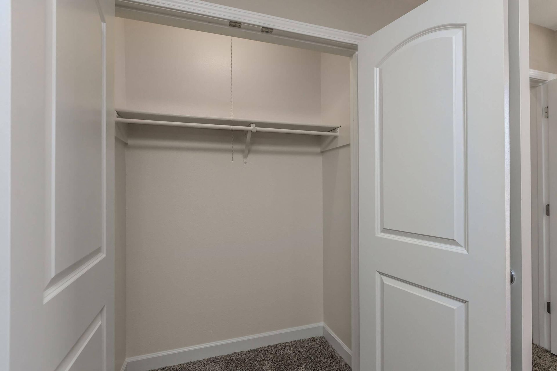 An empty walk in closet with white doors and a carpeted floor at Overbrook Apartments.