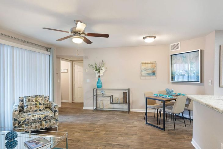 Living room: floral armchair, dining table, ceiling fan, and doorway.
