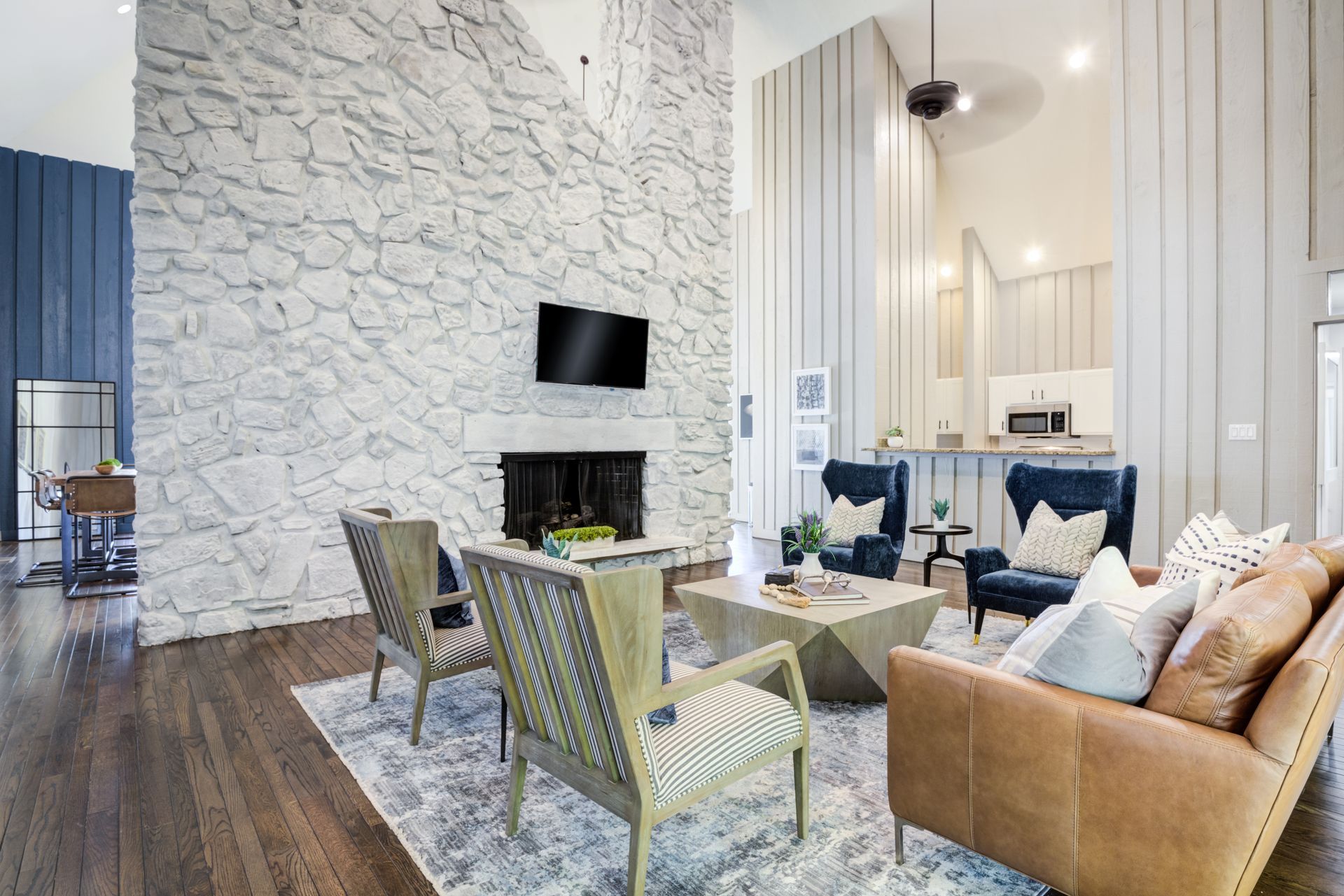 Outdoor patio with seating, sunshade, and a small building, surrounded by trees and blue sky.