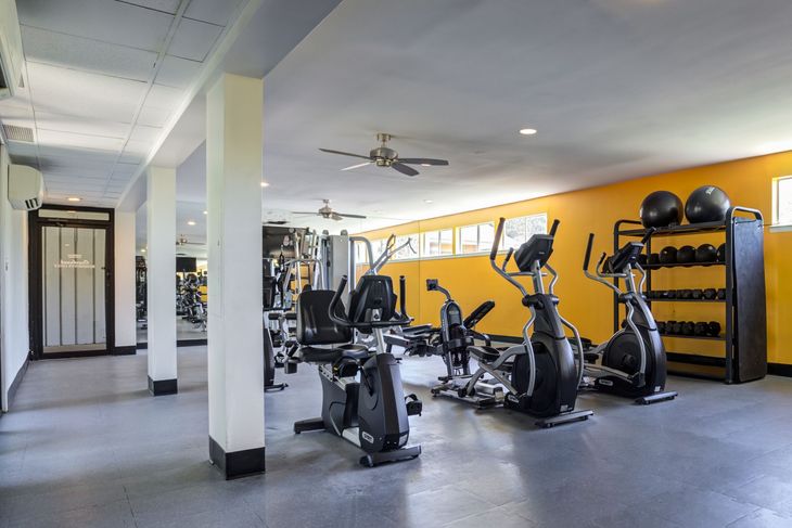 Open-concept room with kitchen and living areas. Gray, white, and blue furnishings. Neutral-toned walls and carpet.