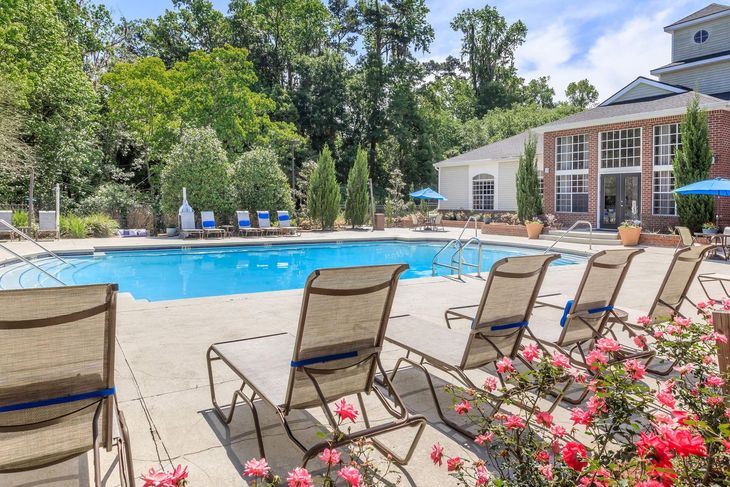 Poolside view with lounge chairs, blue pool, and a building.