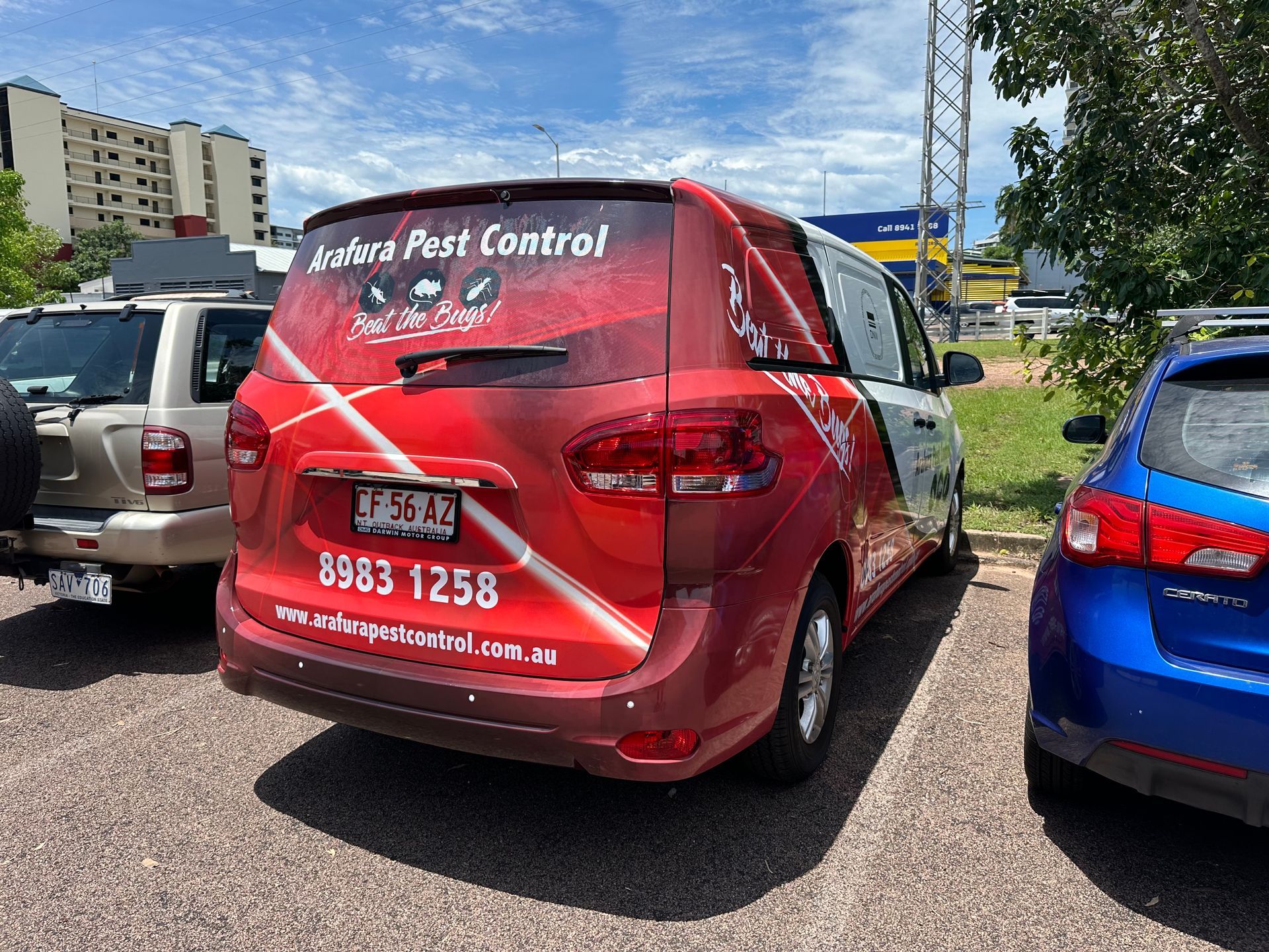 A red van is parked next to a blue car in a parking lot.