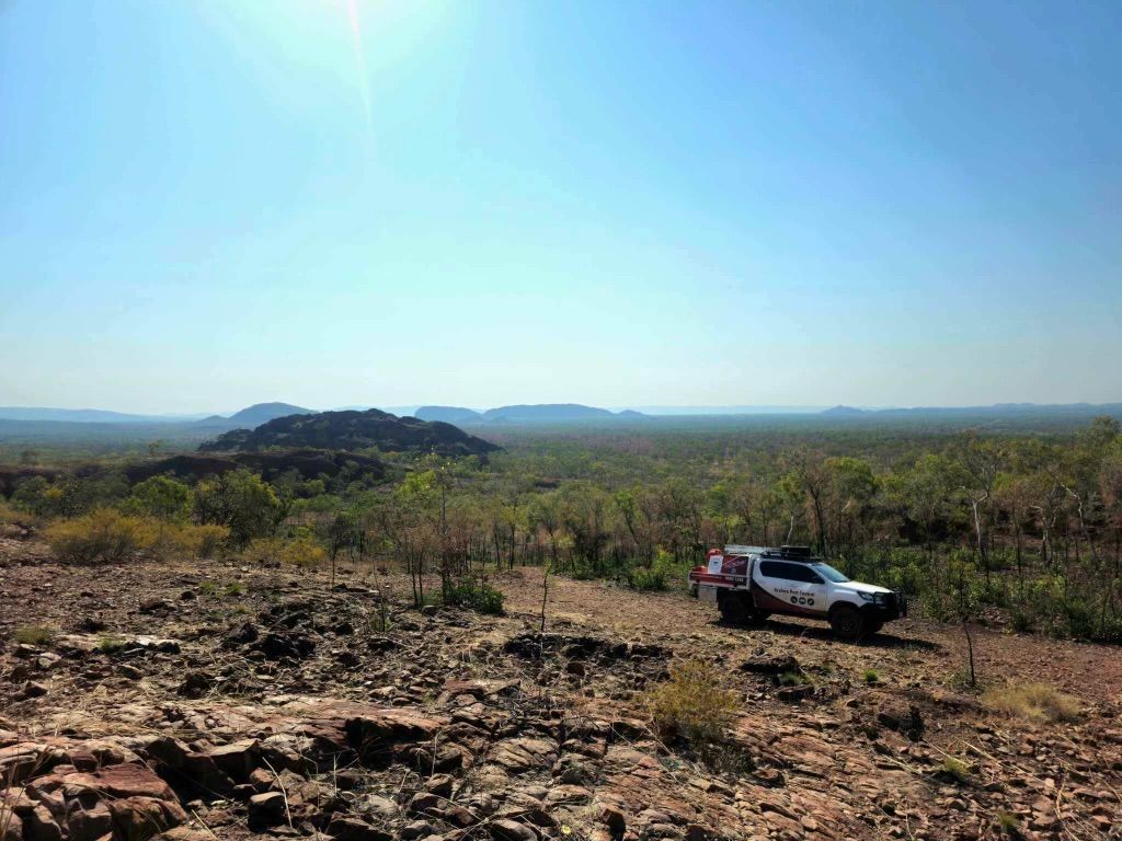 A white truck is parked on top of a rocky hill.