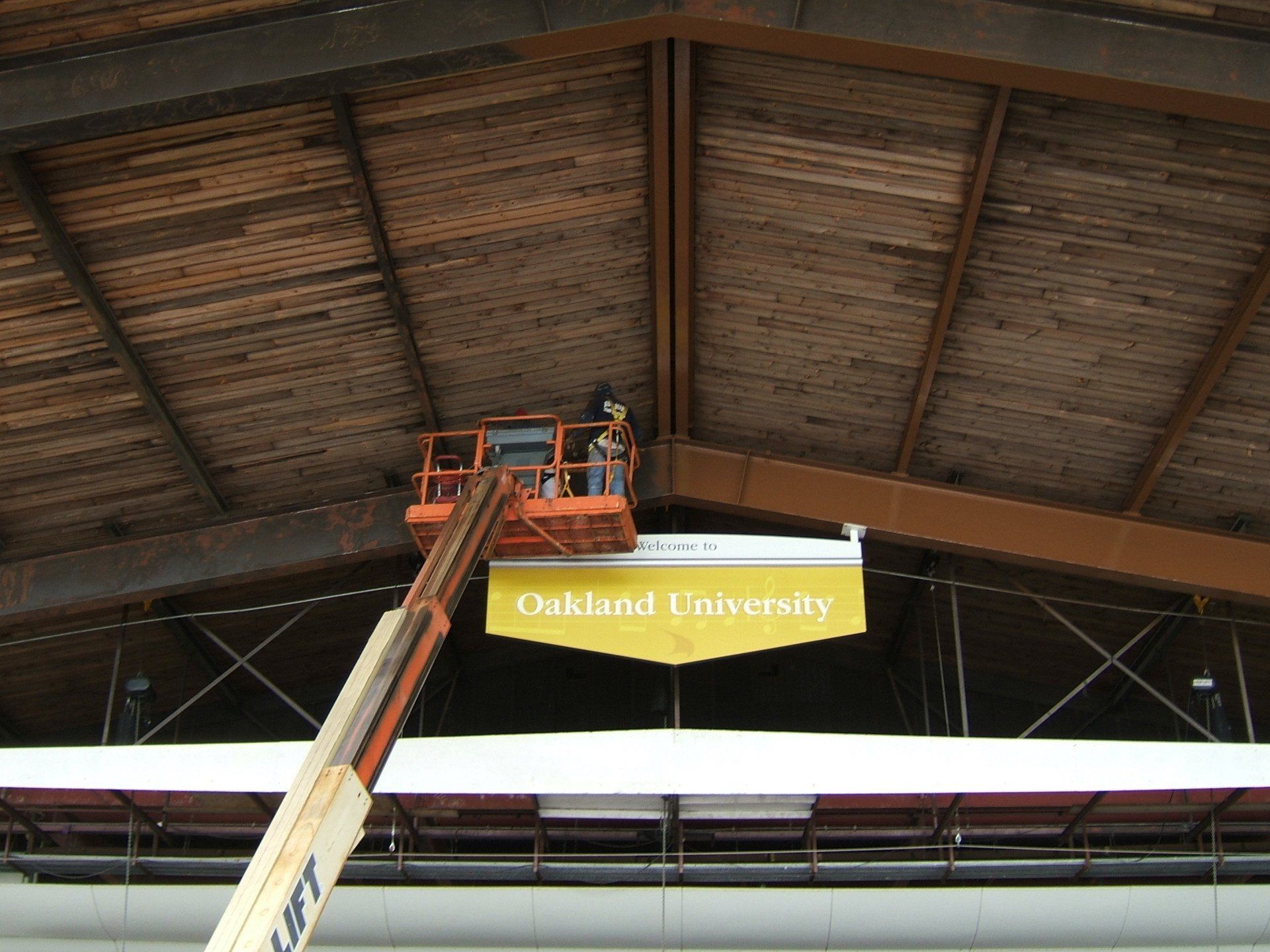 Man fixing Welcome to Oakland University's banner