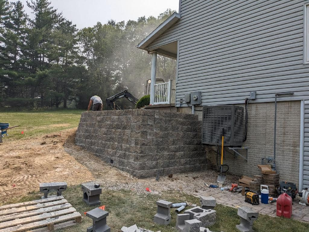 Exterior of a house with a retaining wall and dirt ground.