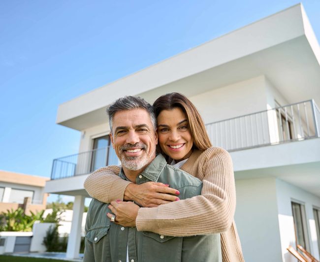 a man and a woman are hugging in front of a house