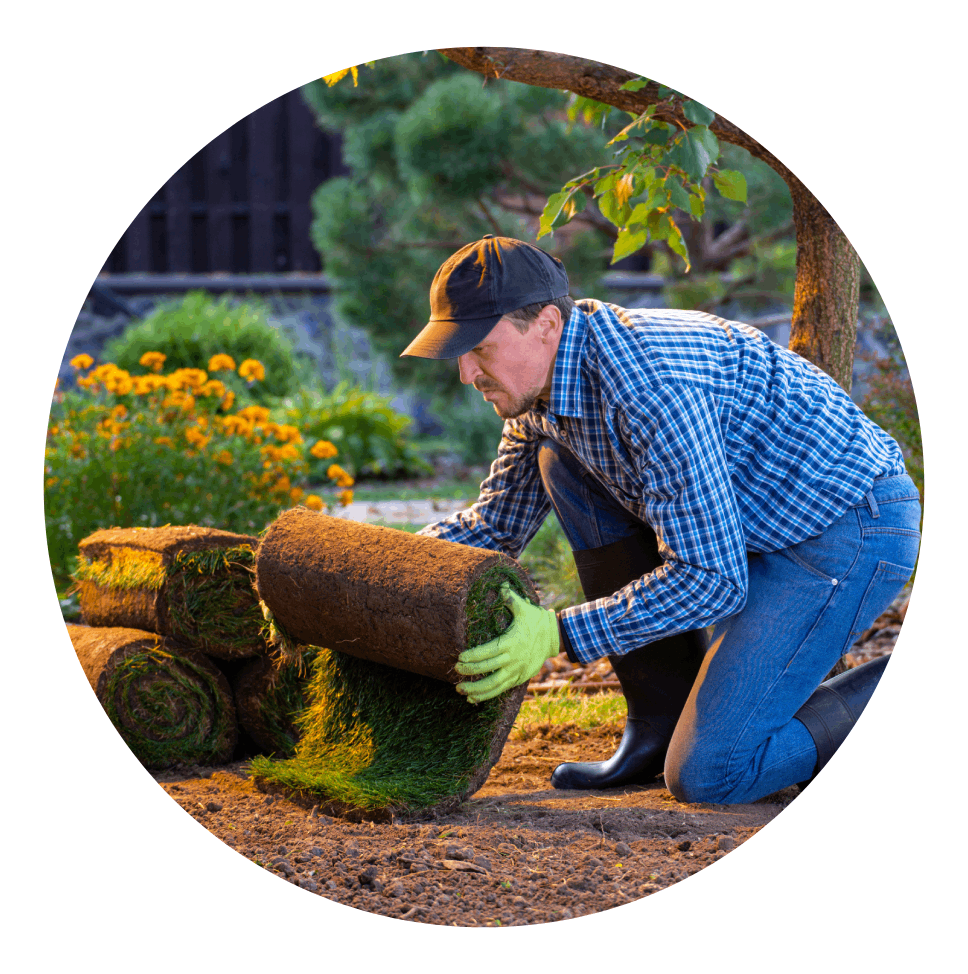 a man is kneeling down and rolling a roll of grass
