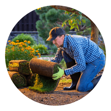 a man is kneeling down and rolling a roll of grass