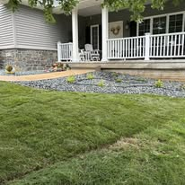 Front of a house with a green lawn and gravel landscaping.