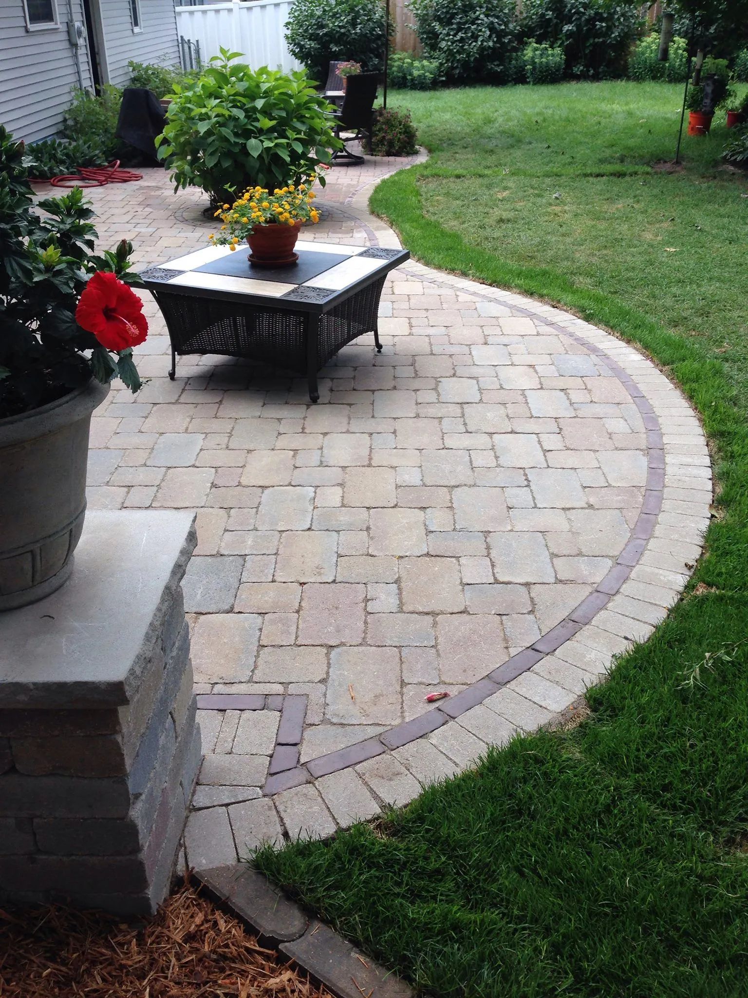 a patio with a fire pit and a potted plant on it