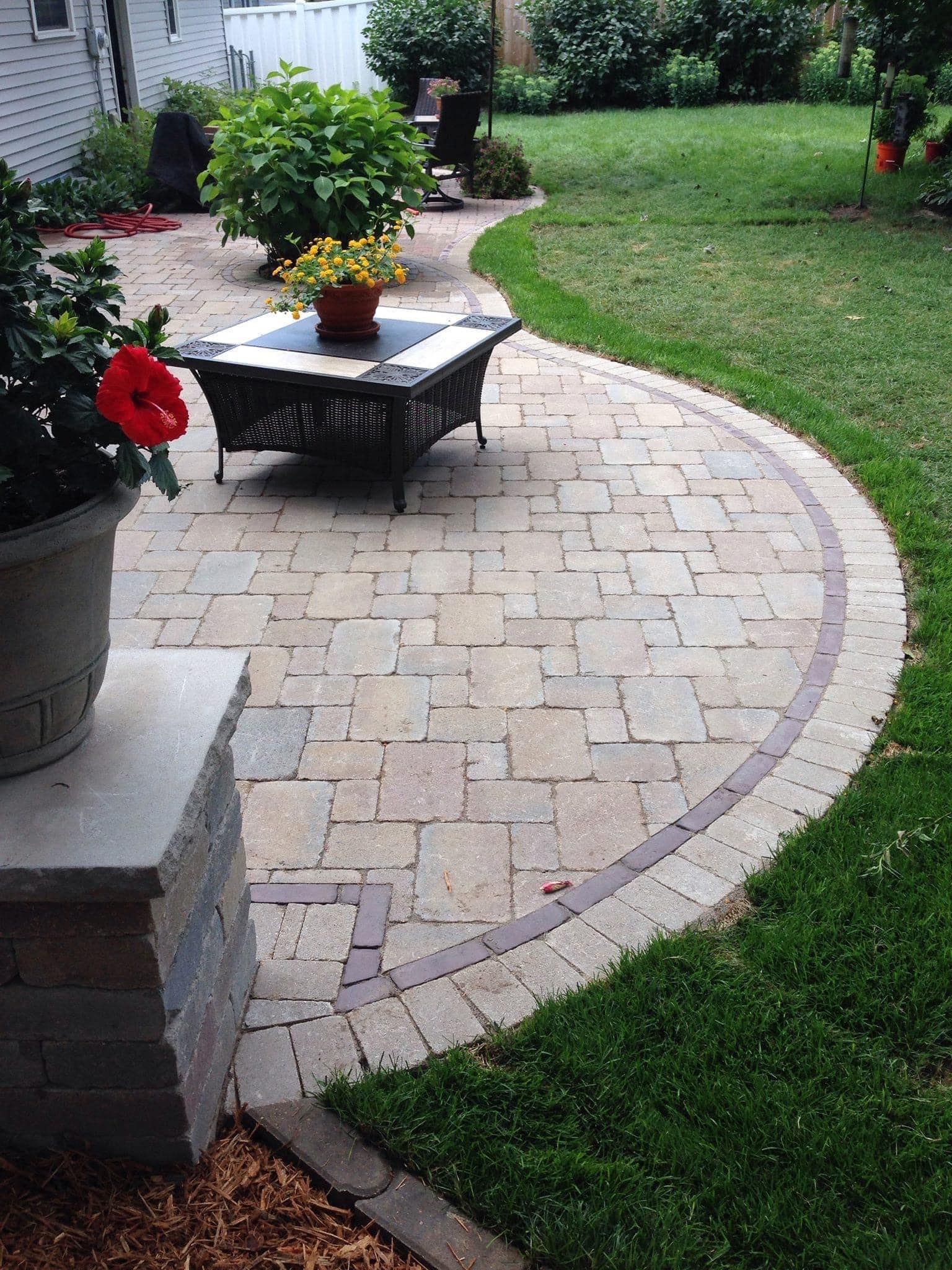 A patio with a fire pit and a potted plant on it.