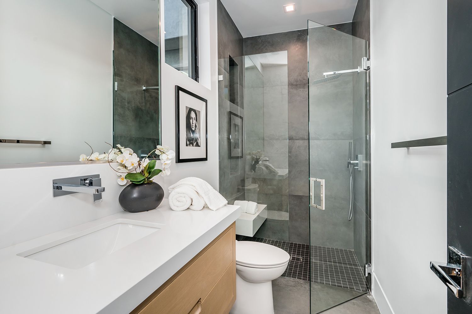 Modern bathroom with frameless glass shower door and sleek gray tile design. Modern bathroom with frameless glass shower door and sleek gray tile design.