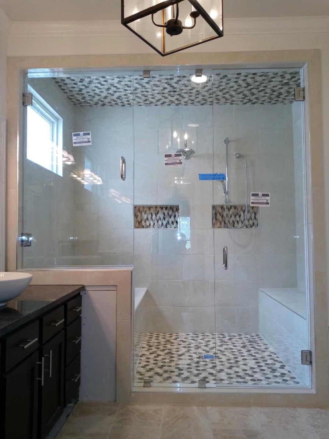 A modern bathroom with a large glass shower enclosure featuring mosaic tile accents and a built-in bench.