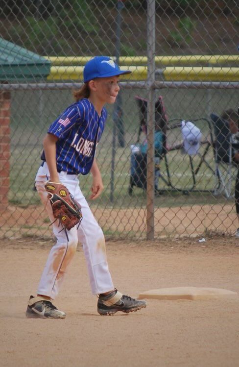 A young boy is playing baseball on a dirt field.