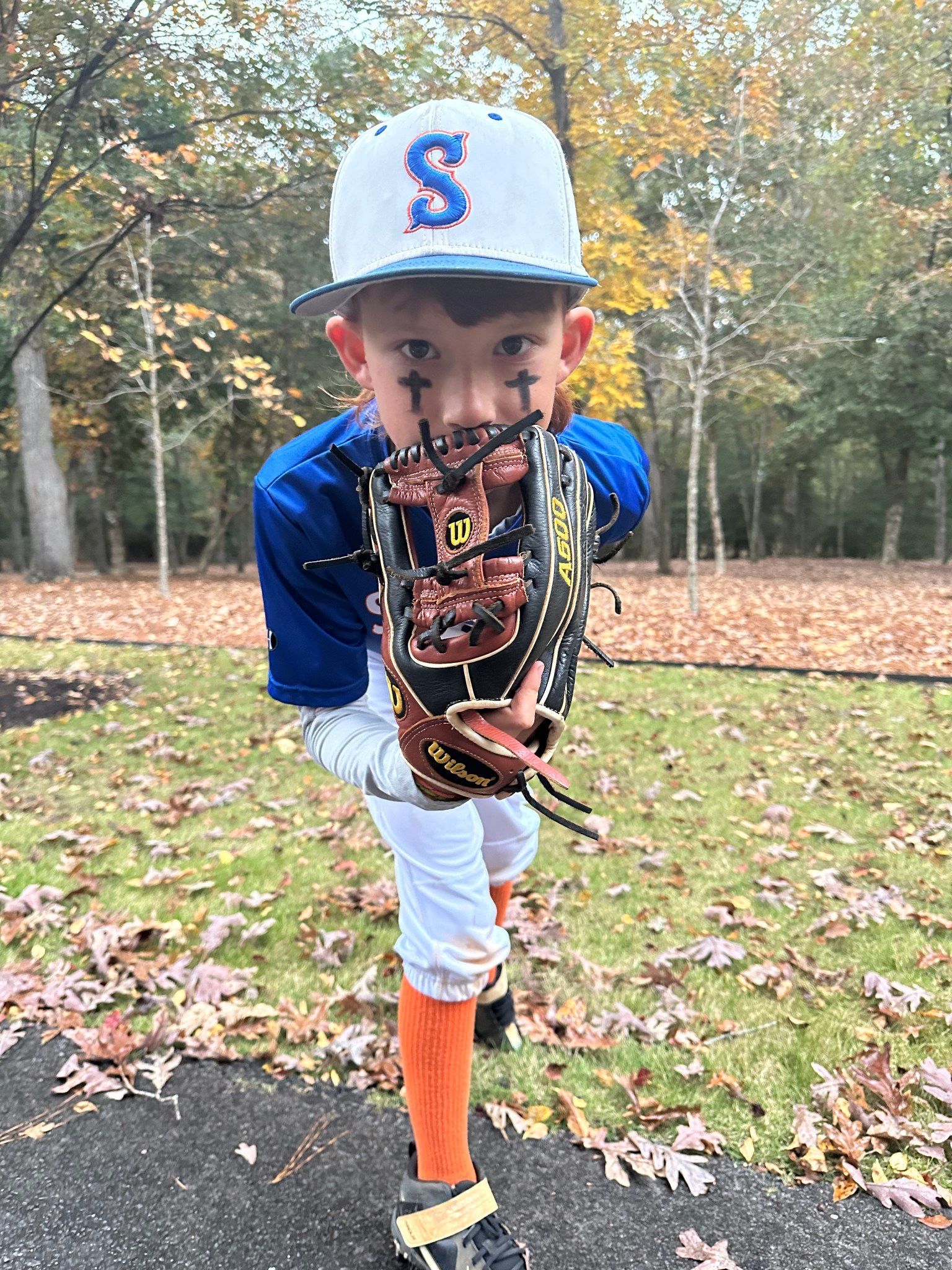 A young boy in a baseball uniform is holding a baseball glove.