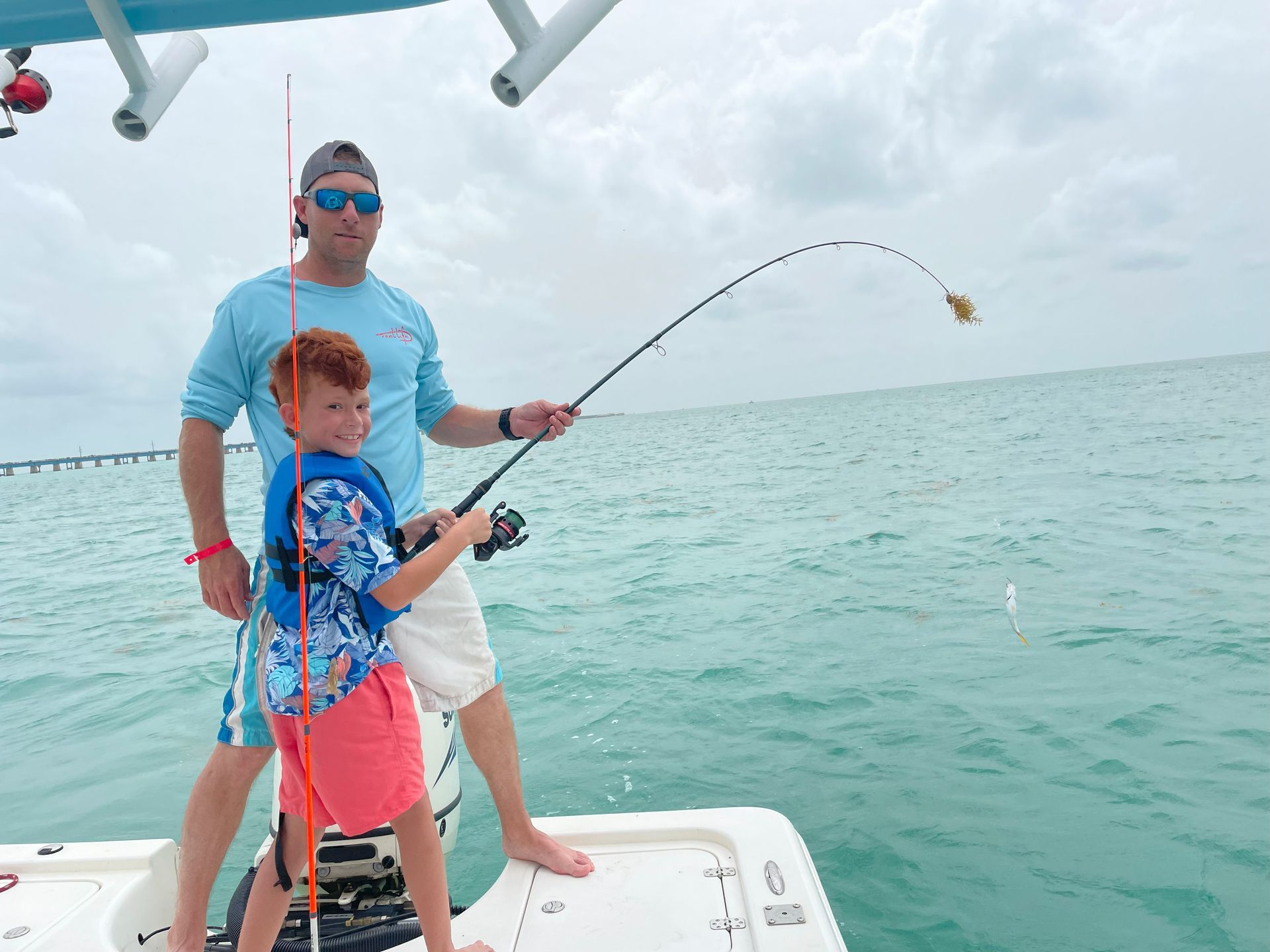 A man and a boy are fishing on a boat in the ocean.