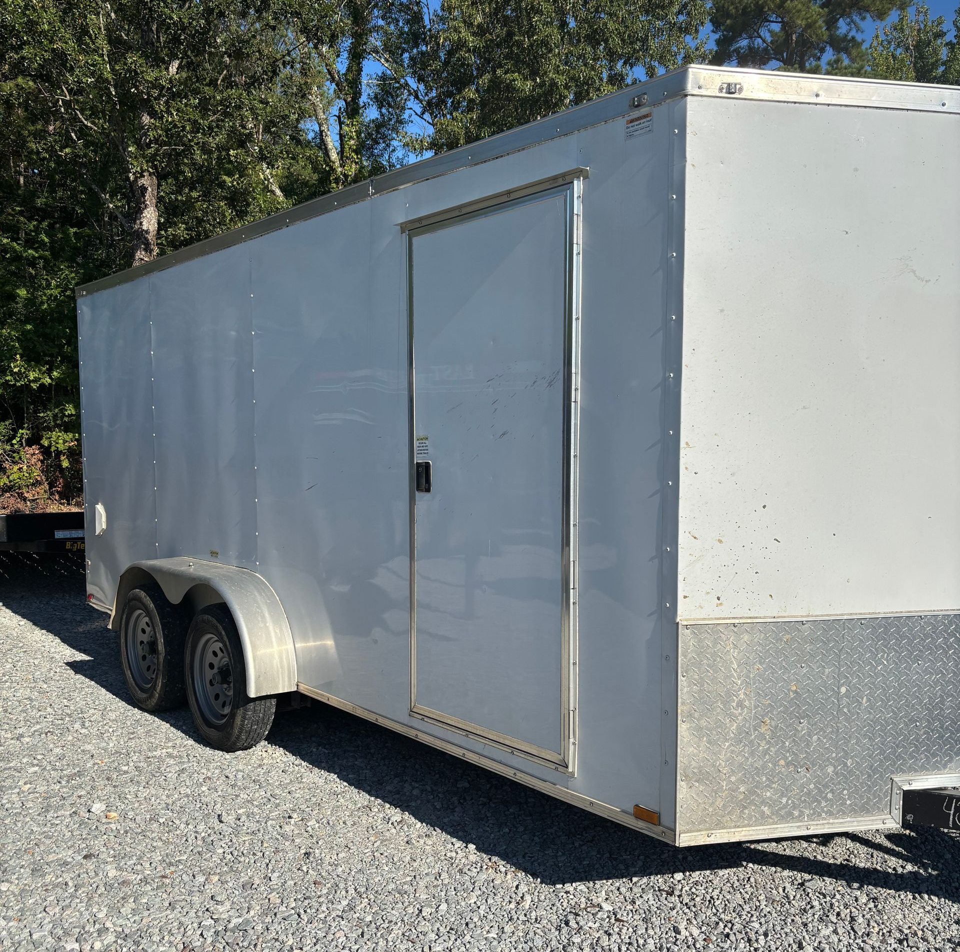 Silver enclosed trailer parked on gravel.