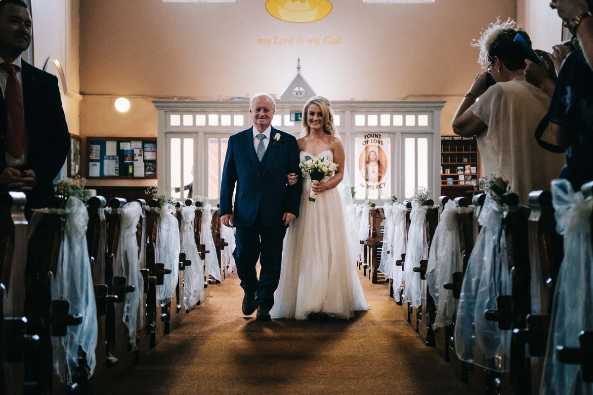 bride and father walking together down church aisle 
