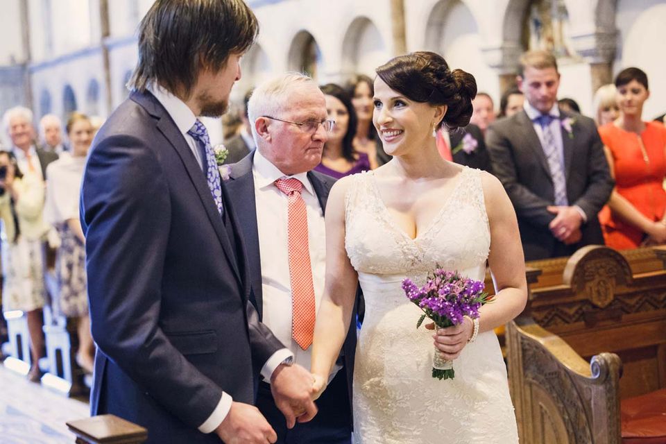 wedding couple holding hands at the end of aisle at Honan Chapel UCC