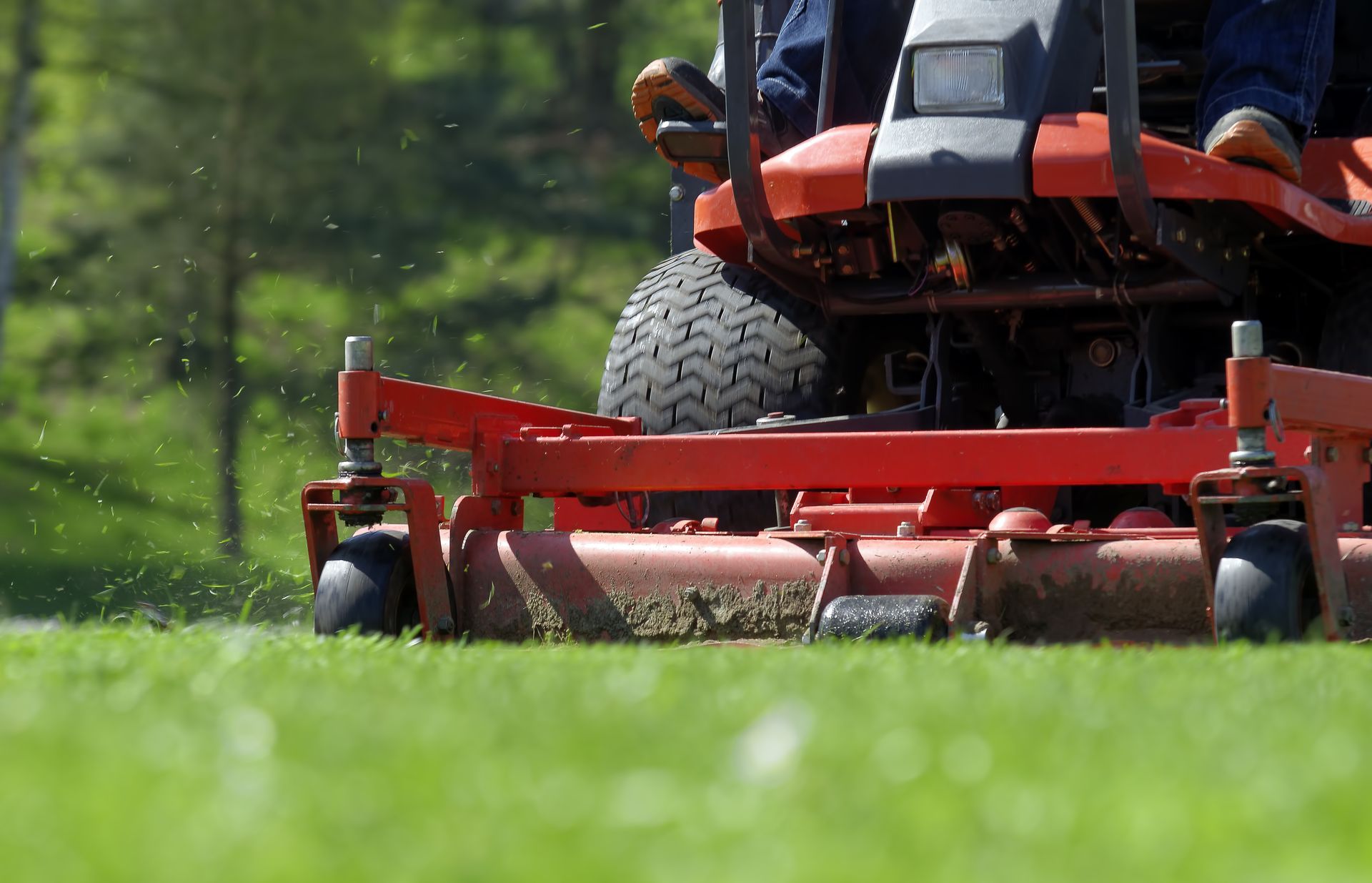 A man is riding a lawn mower on a lush green field.