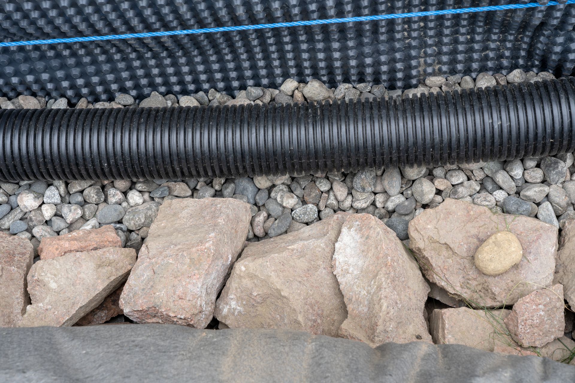 A black pipe is sitting on top of a pile of rocks.