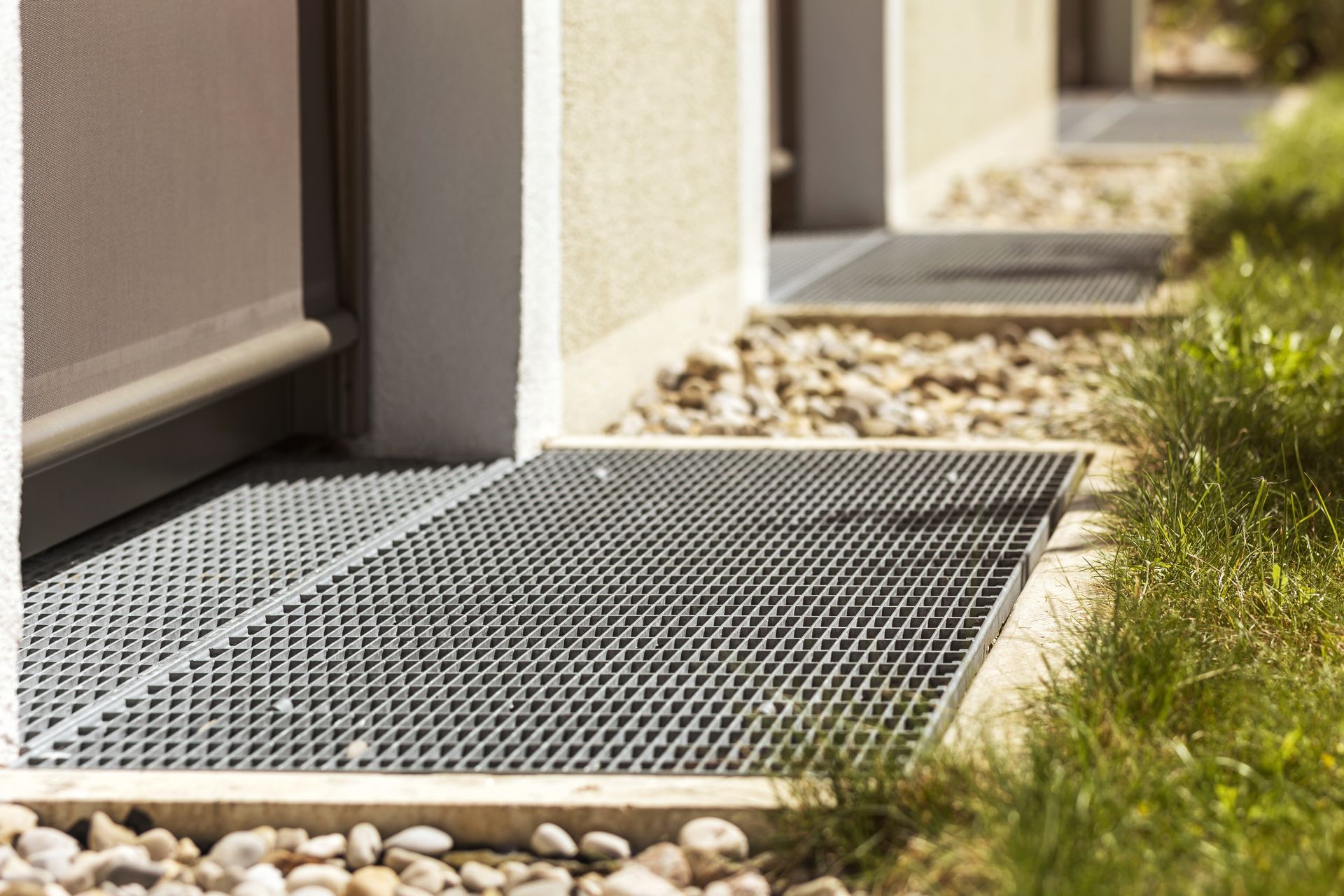 A metal grate is sitting on the ground next to a door.