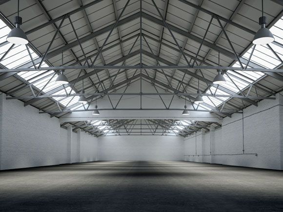An empty warehouse with a lot of windows and a roof.
