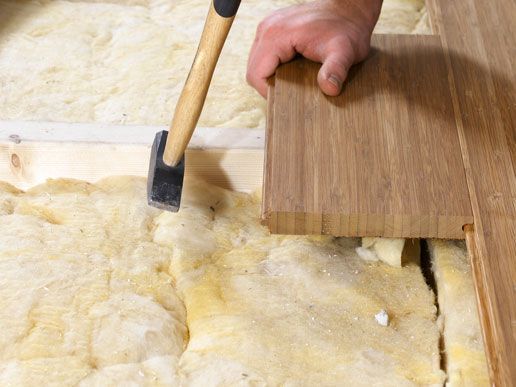 A person is holding a hammer over a piece of wood.