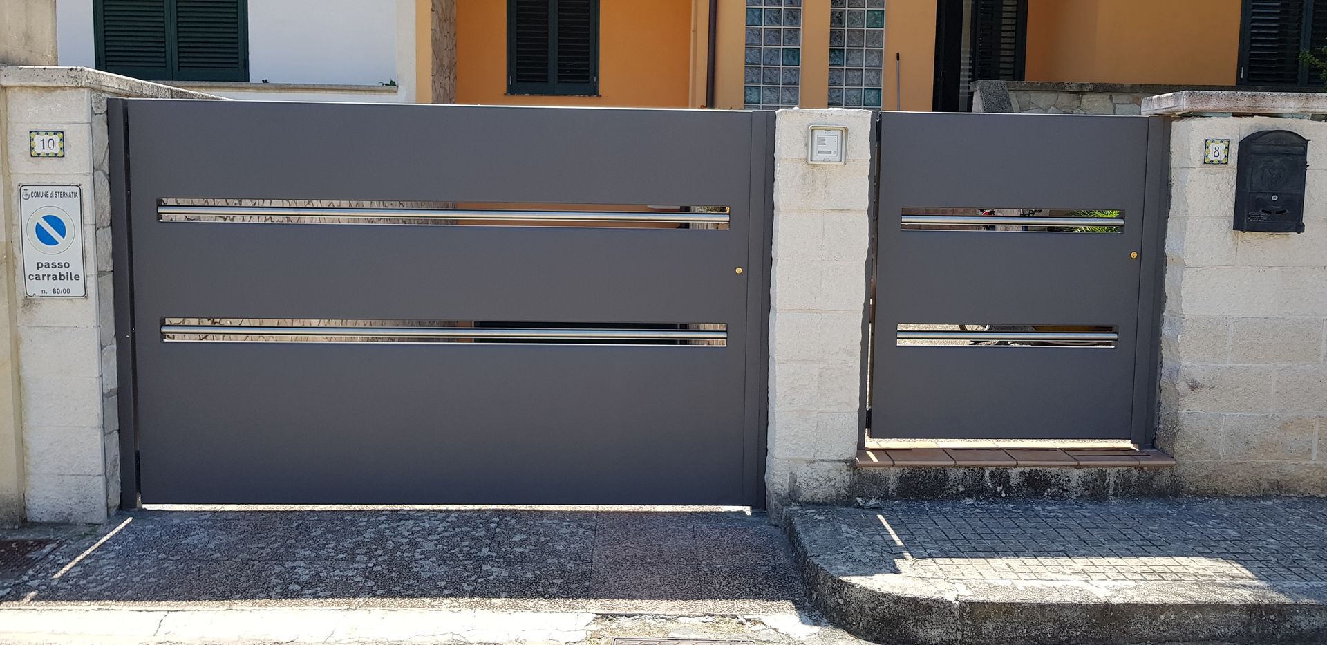 Un cancello nero è posto davanti a una casa.