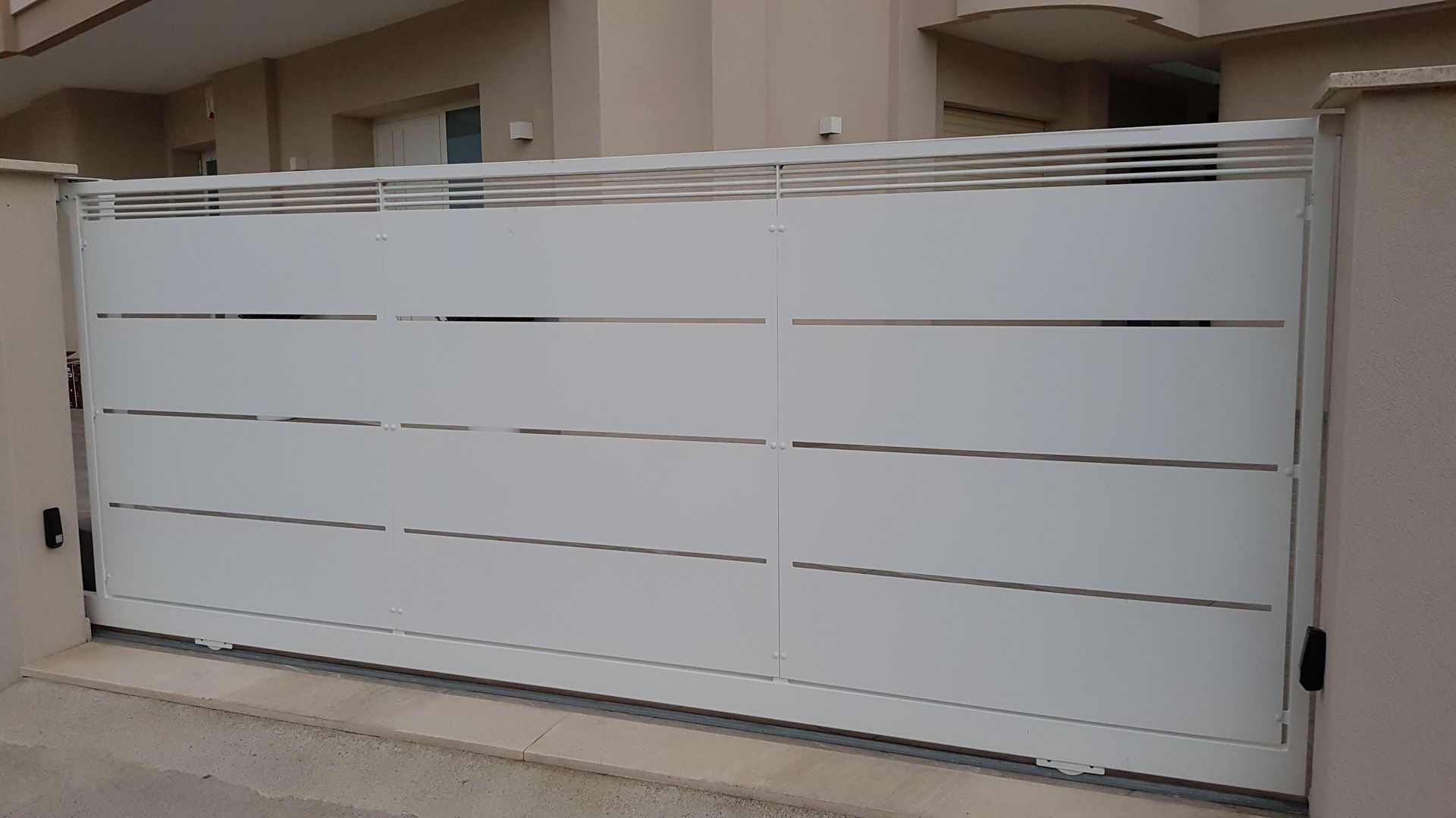 Un cancello scorrevole bianco è posto di fronte a un edificio.