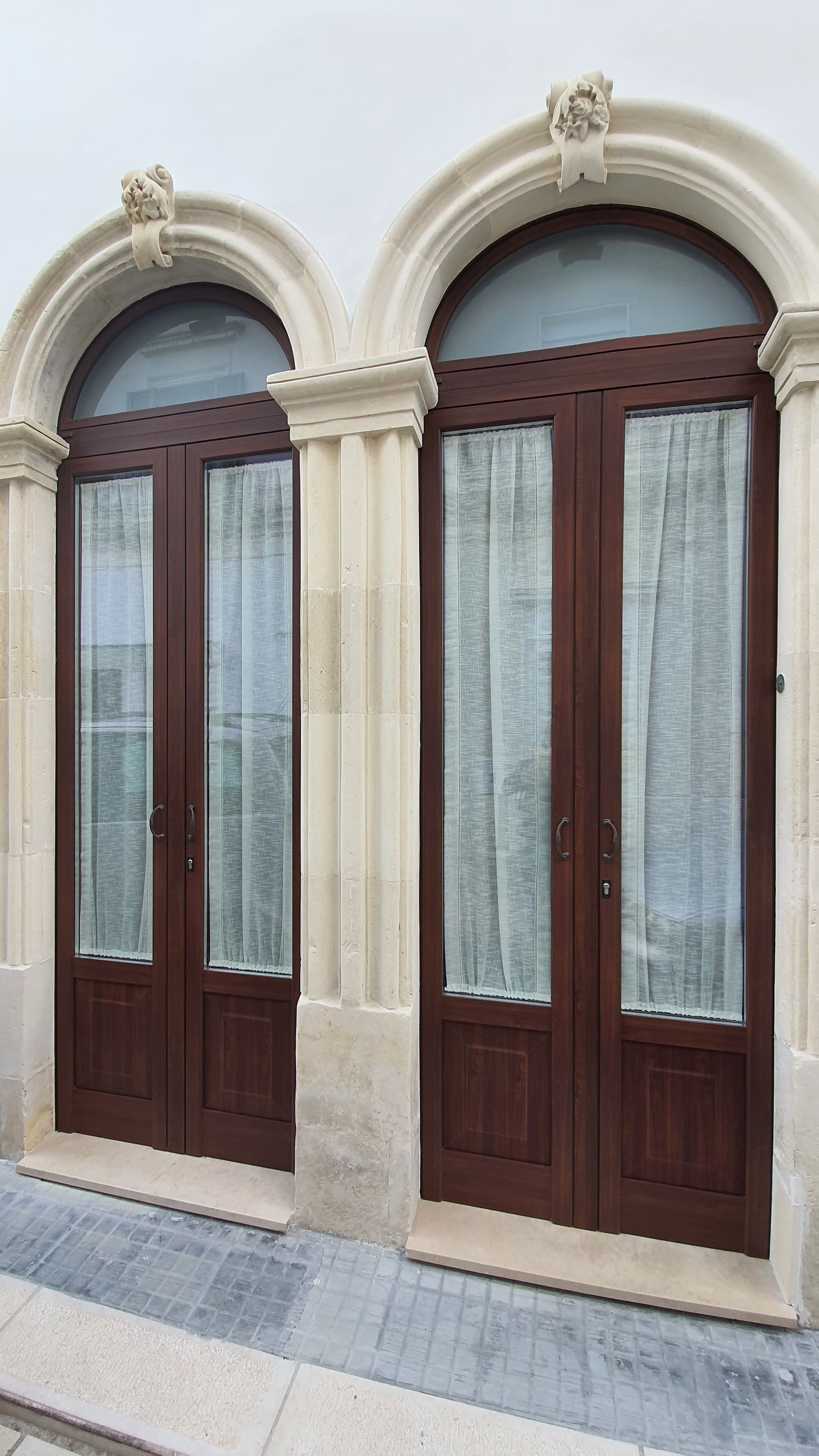 Una coppia di porte di legno con finestre ad arco su un edificio.