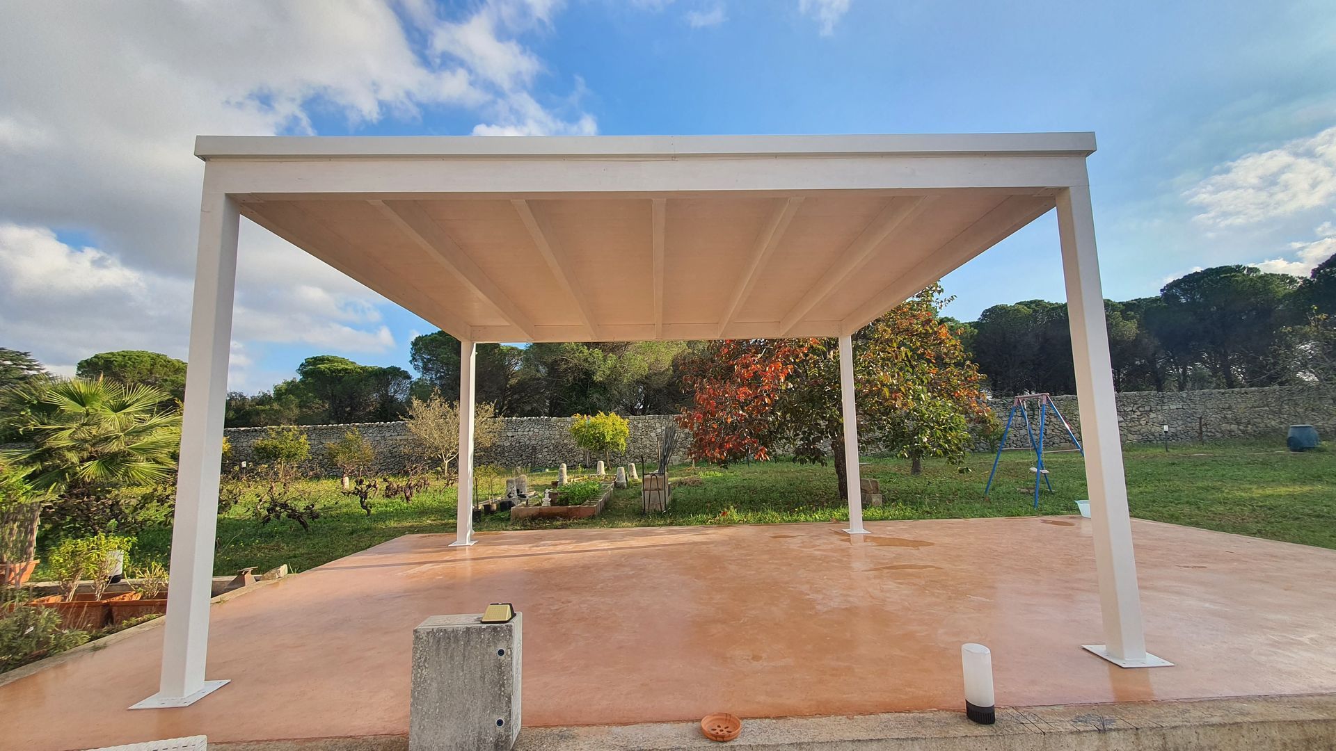 Un pergolato bianco è posto sopra un patio in cemento.