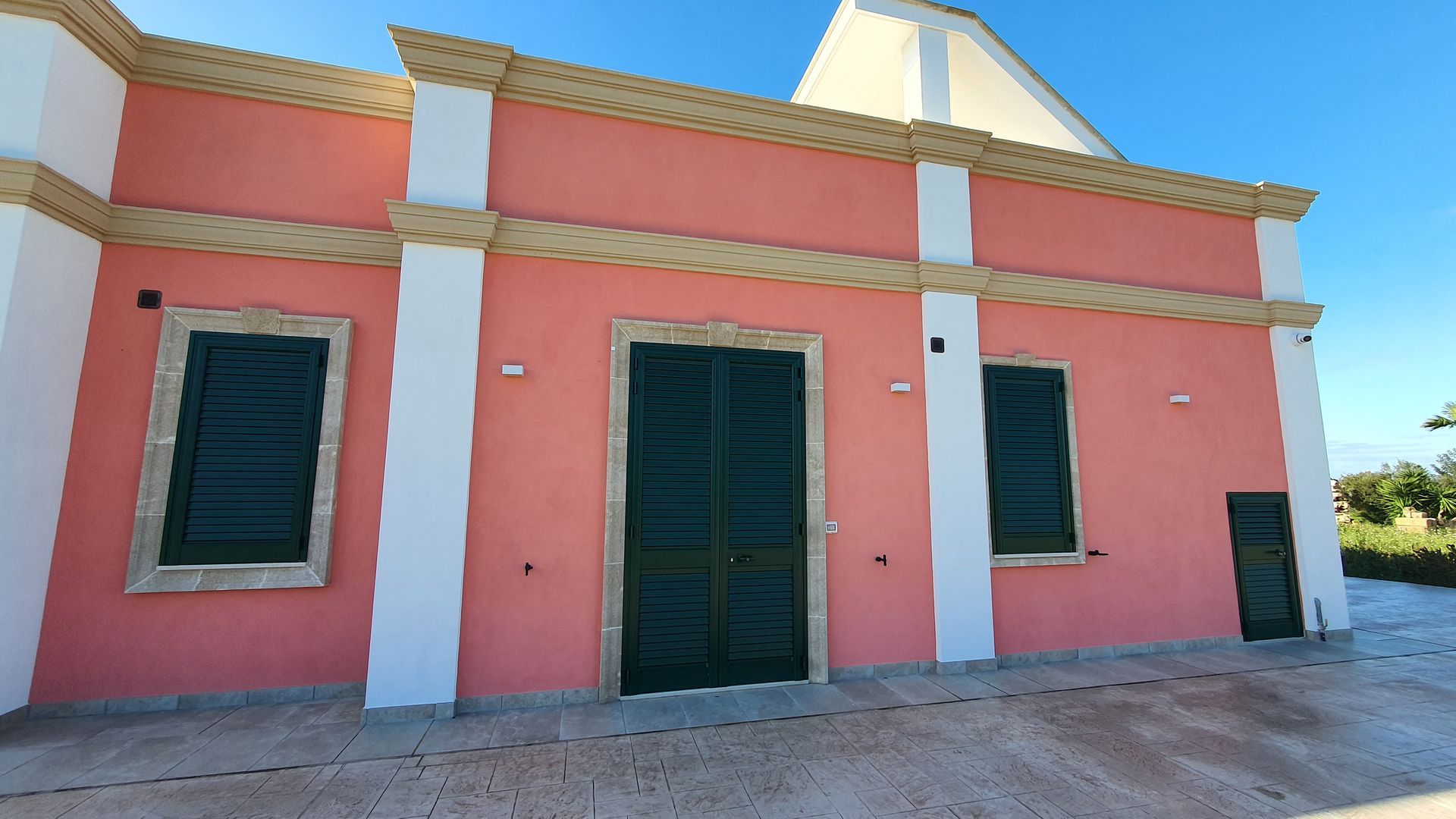 Un edificio rosa e bianco con porte e finestre verdi