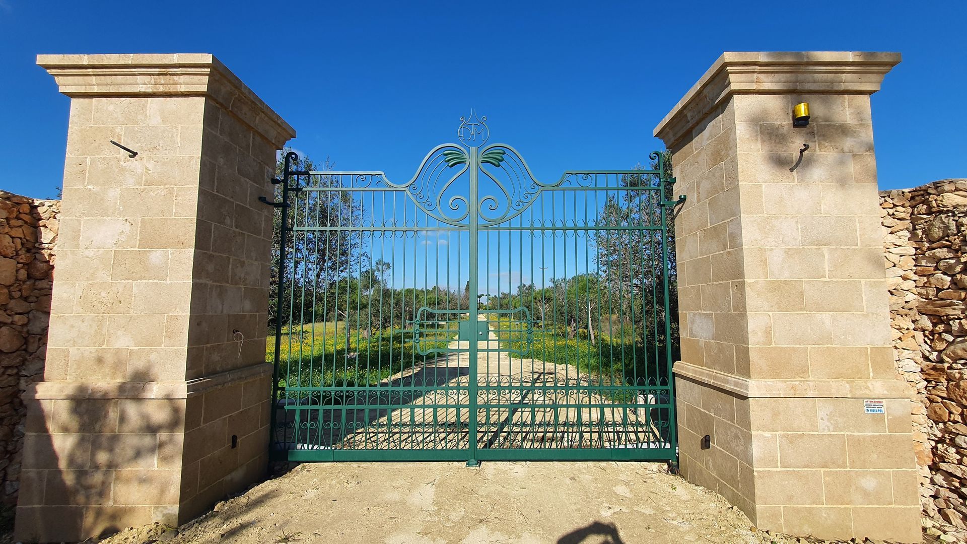 Un cancello verde è tra due pilastri di pietra.