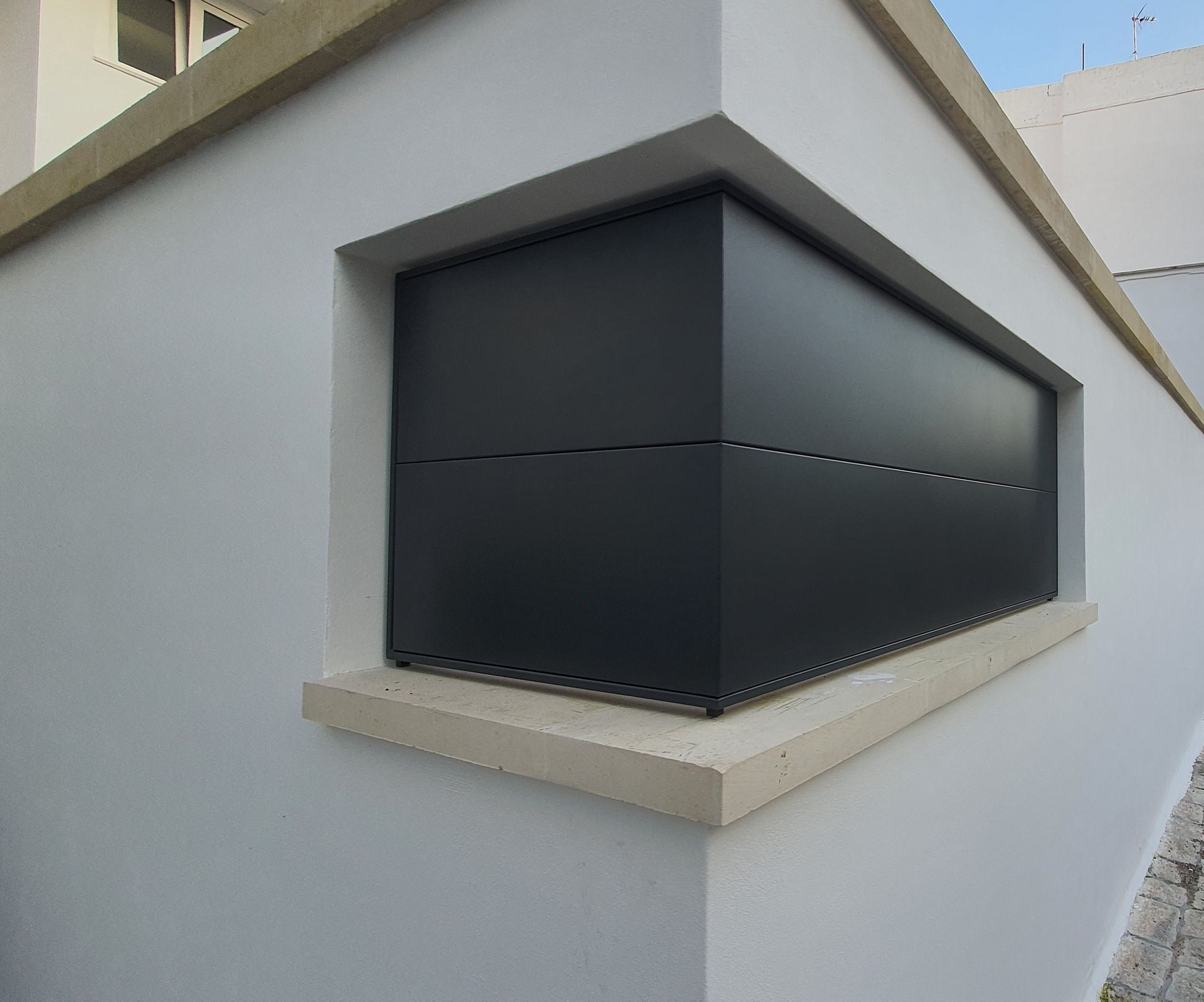 Un muro bianco con un angolo nero e una finestra