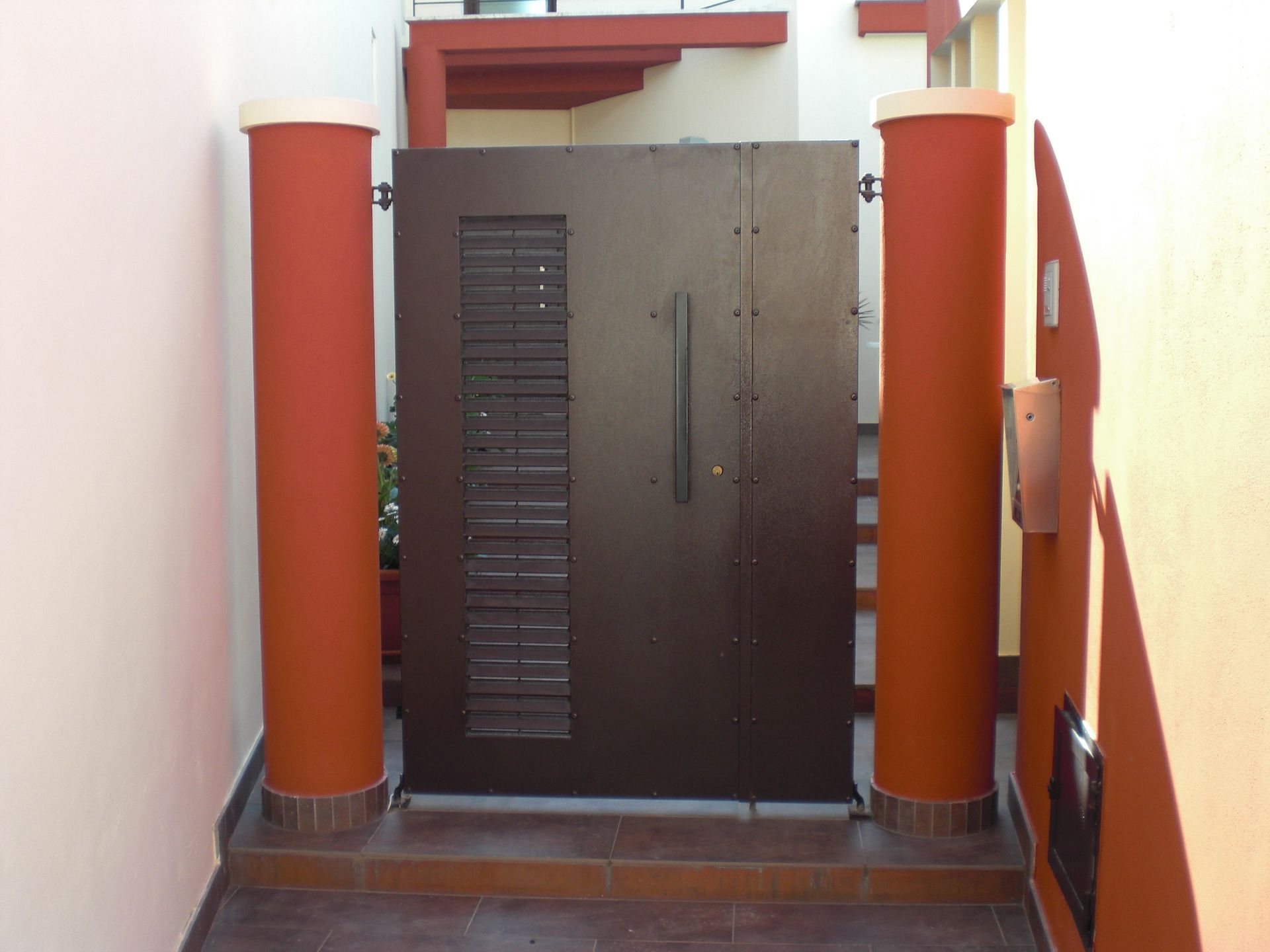 Un cancello marrone è circondato da due pilastri rossi