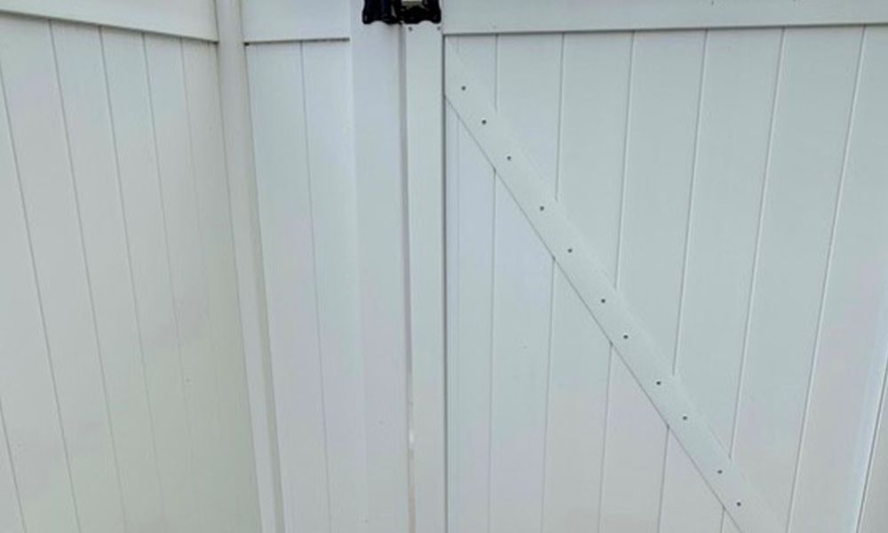 A close up of a white wooden gate with a black handle.