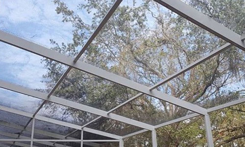 A clear roof of a screened in porch with trees in the background.