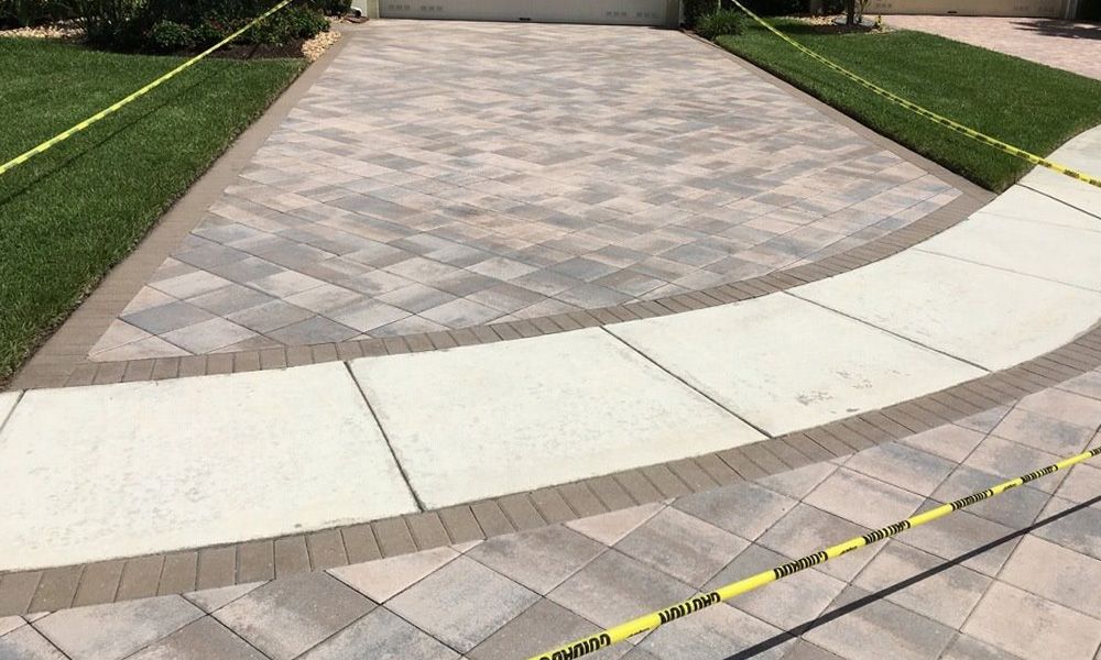 A brick driveway with a walkway leading to a house.