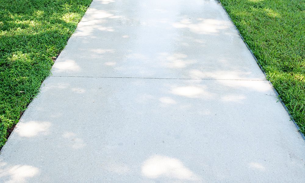 A concrete sidewalk going through a lush green field.
