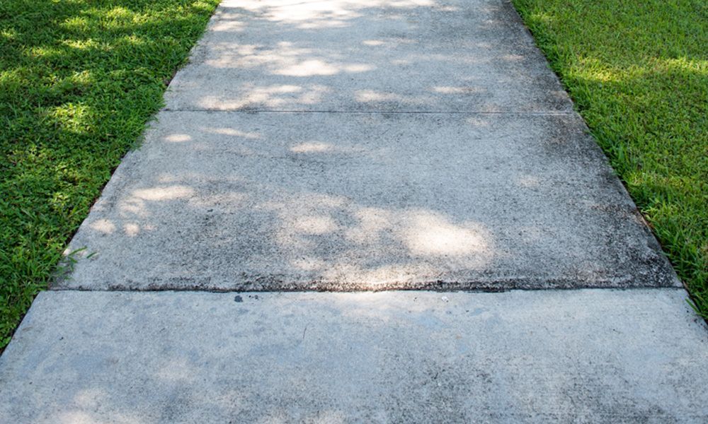 A concrete sidewalk leading to a grassy field.