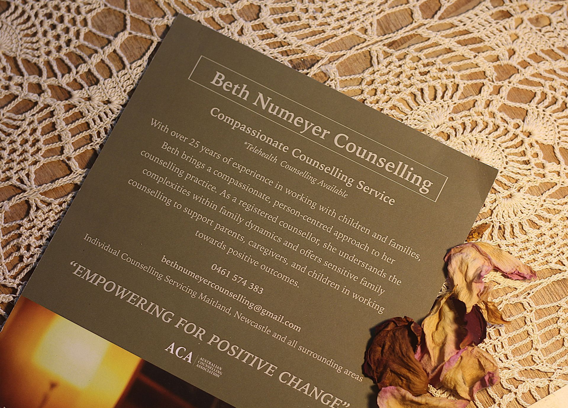 Beige brochure for beach nursery consulting on a lace tablecloth, with dried flowers beside it.