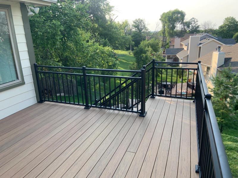 A wooden deck with a black railing and stairs