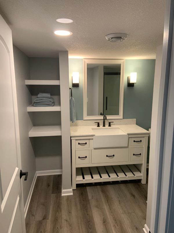A bathroom with a sink , mirror and shelves