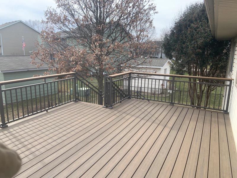 A large wooden deck with a metal railing and stairs leading up to it.
