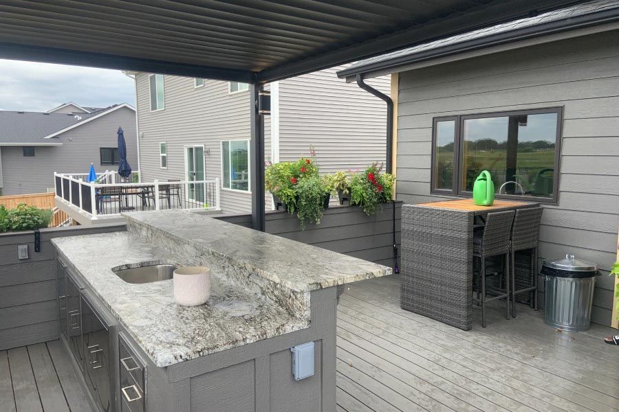 A large outdoor kitchen with a sink and a table on a deck.