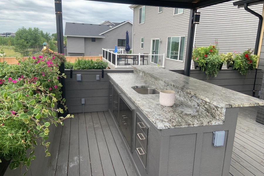 A kitchen on a deck with a sink and flowers.