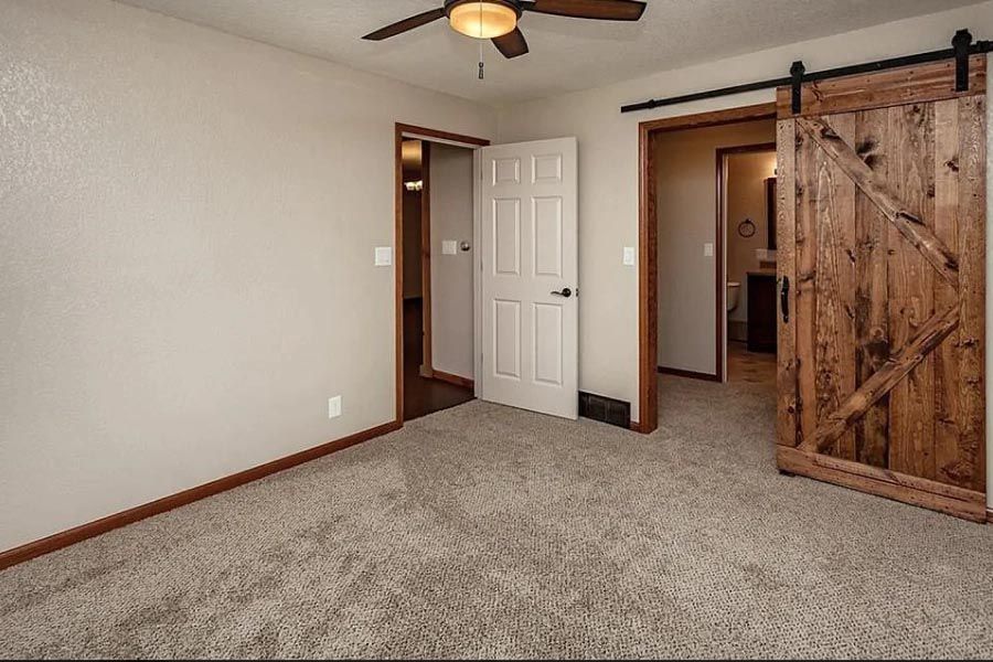 A bedroom with a sliding barn door and a ceiling fan.