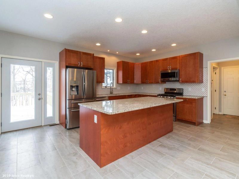 A kitchen with wooden cabinets , granite counter tops , stainless steel appliances and a large island.